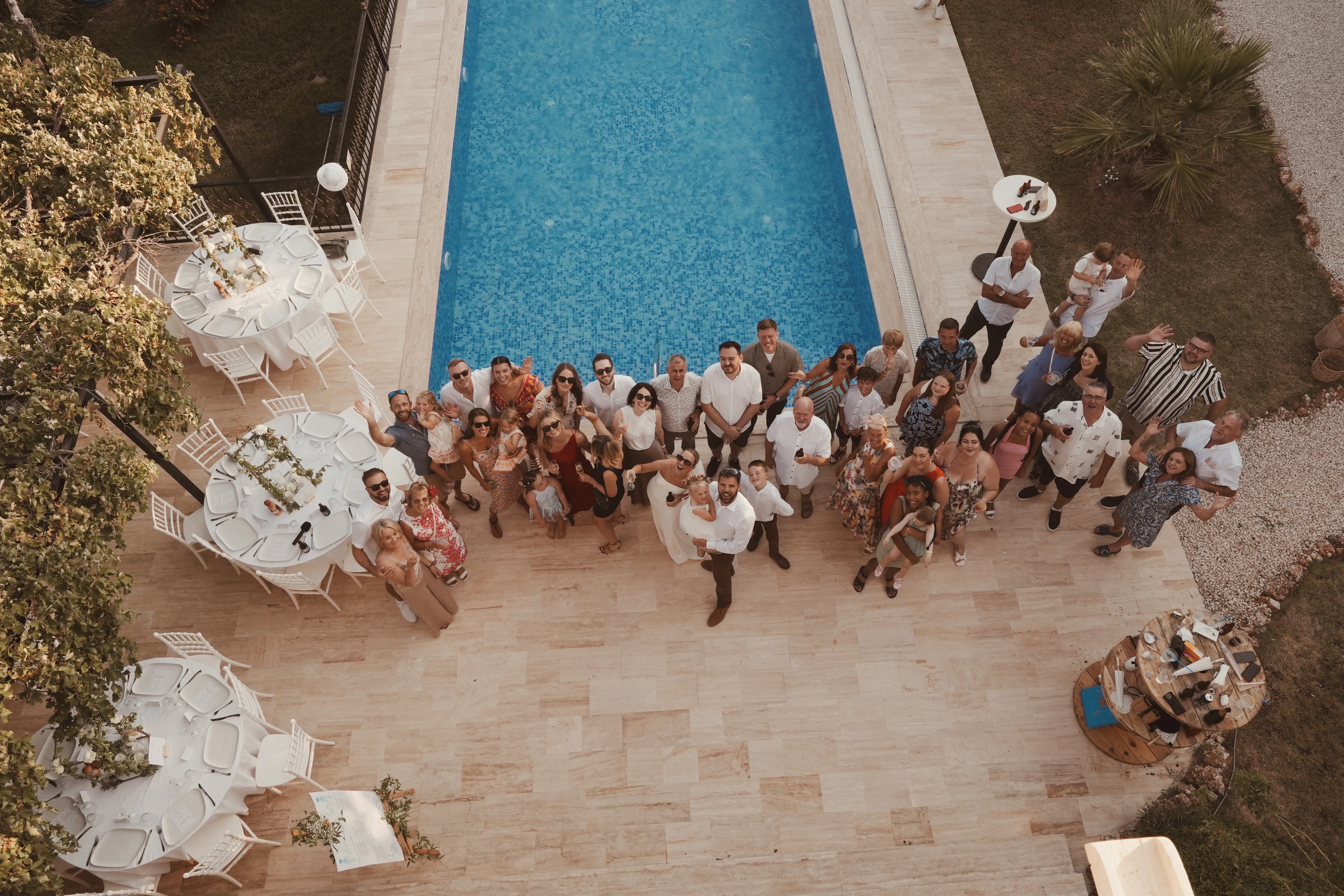 Aerial view of wedding party gathered around villa pool