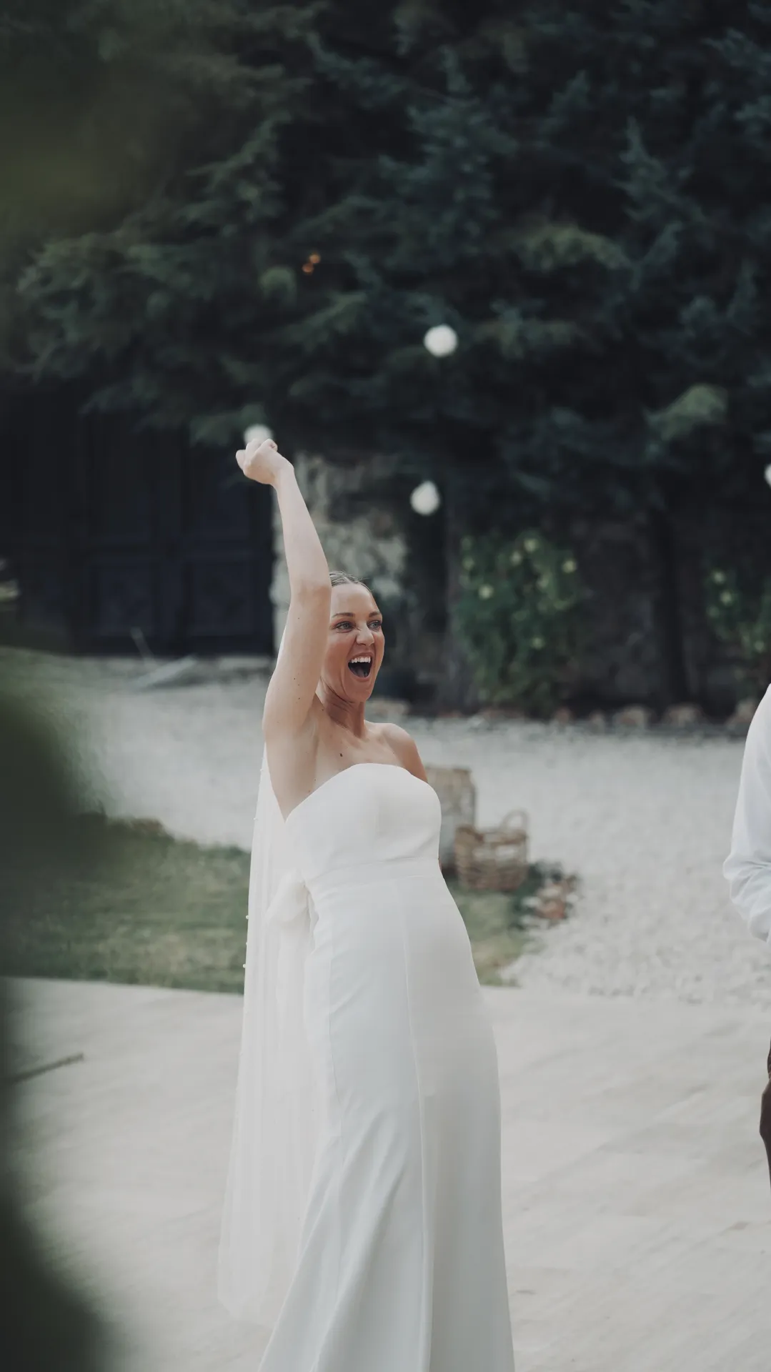 Joyful bride celebrating with arms raised in garden ceremony