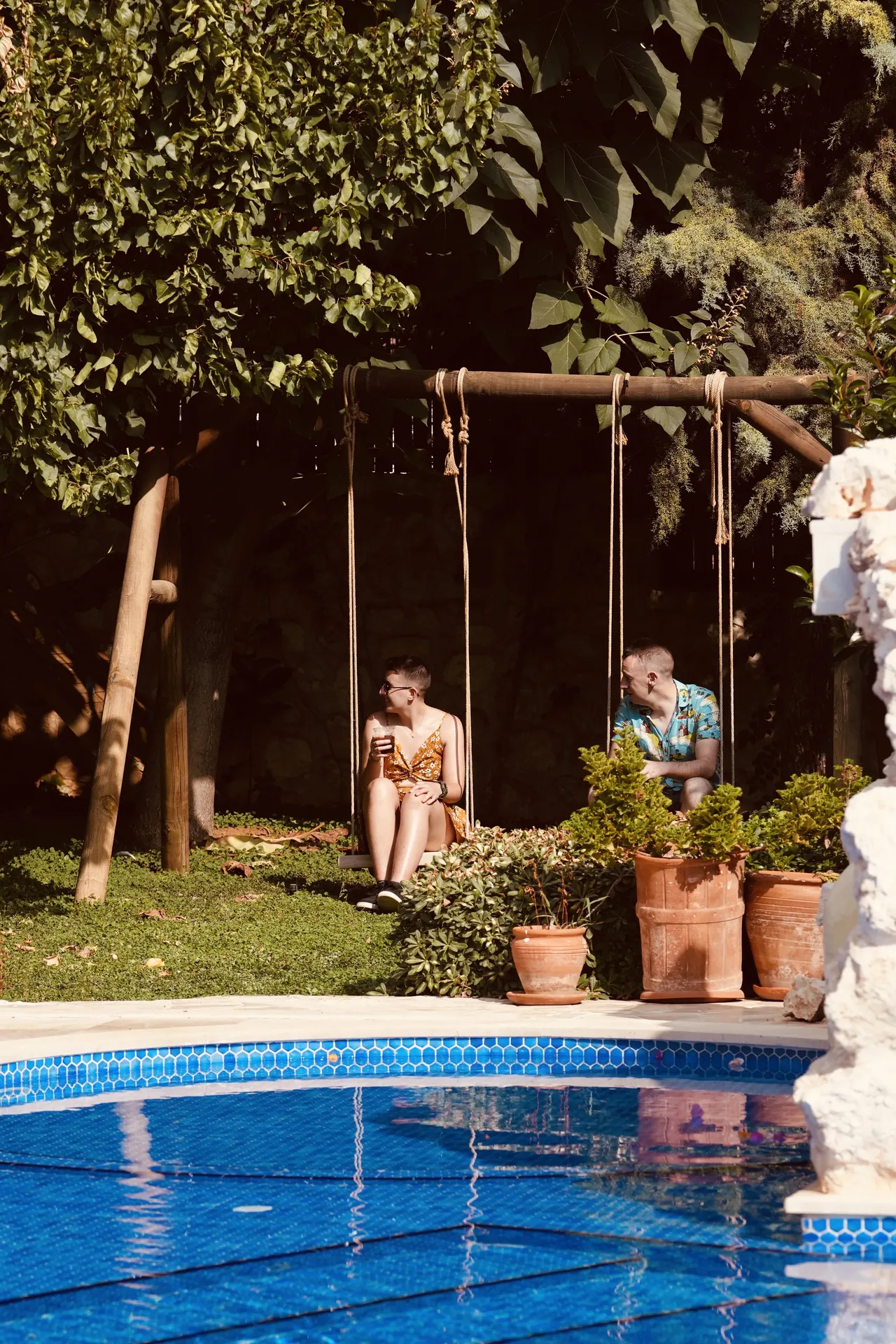 Children playing on wooden swings by villa pool