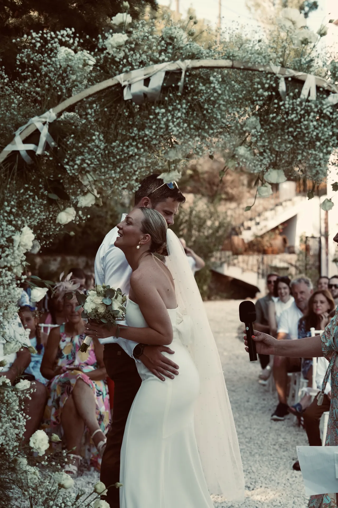 Couple kissing under circular baby's breath arch with confetti