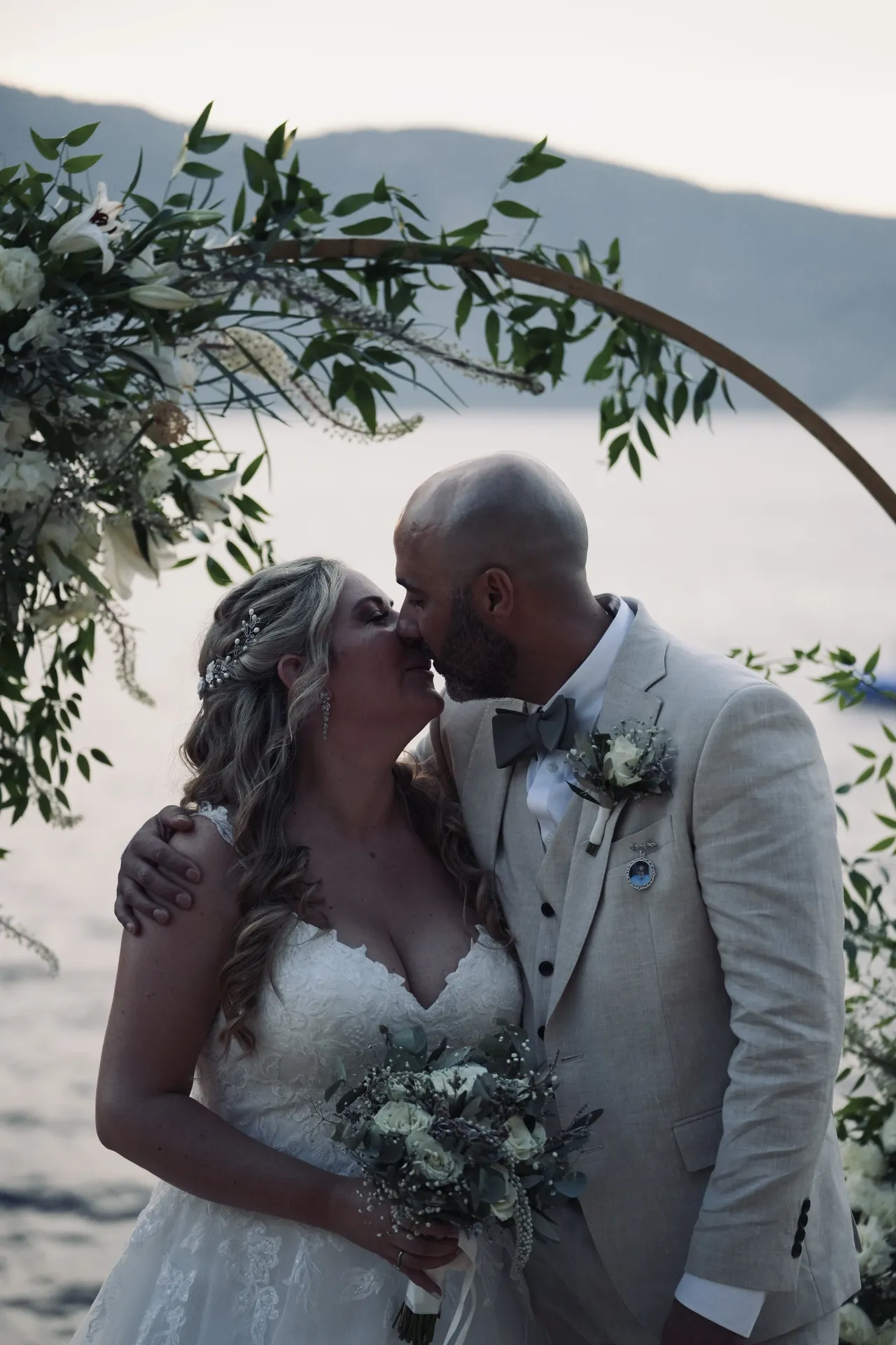 Couple kissing under floral arch at dusk with golden light