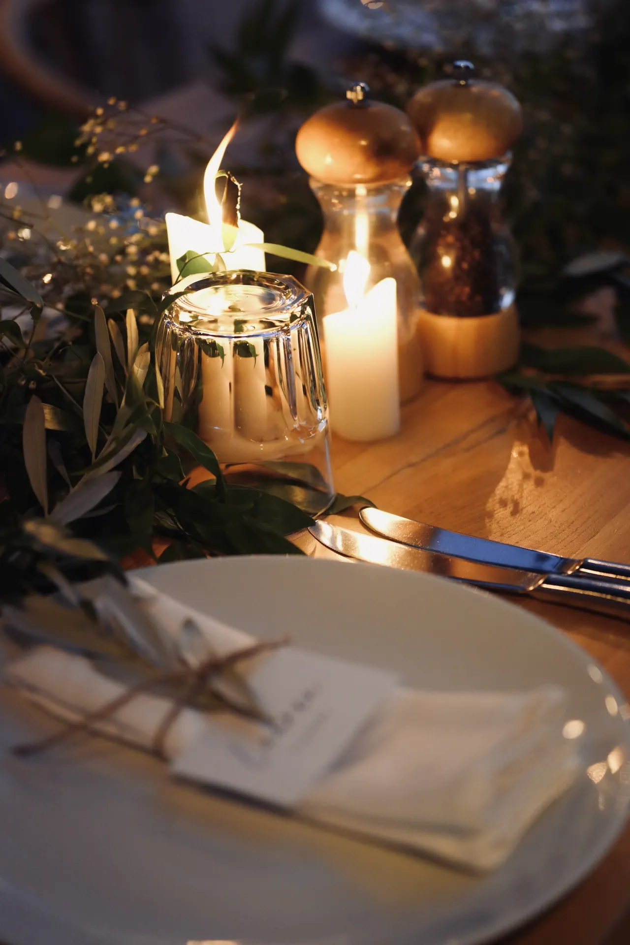 Fine dining table setting with candles and olive branch centerpiece