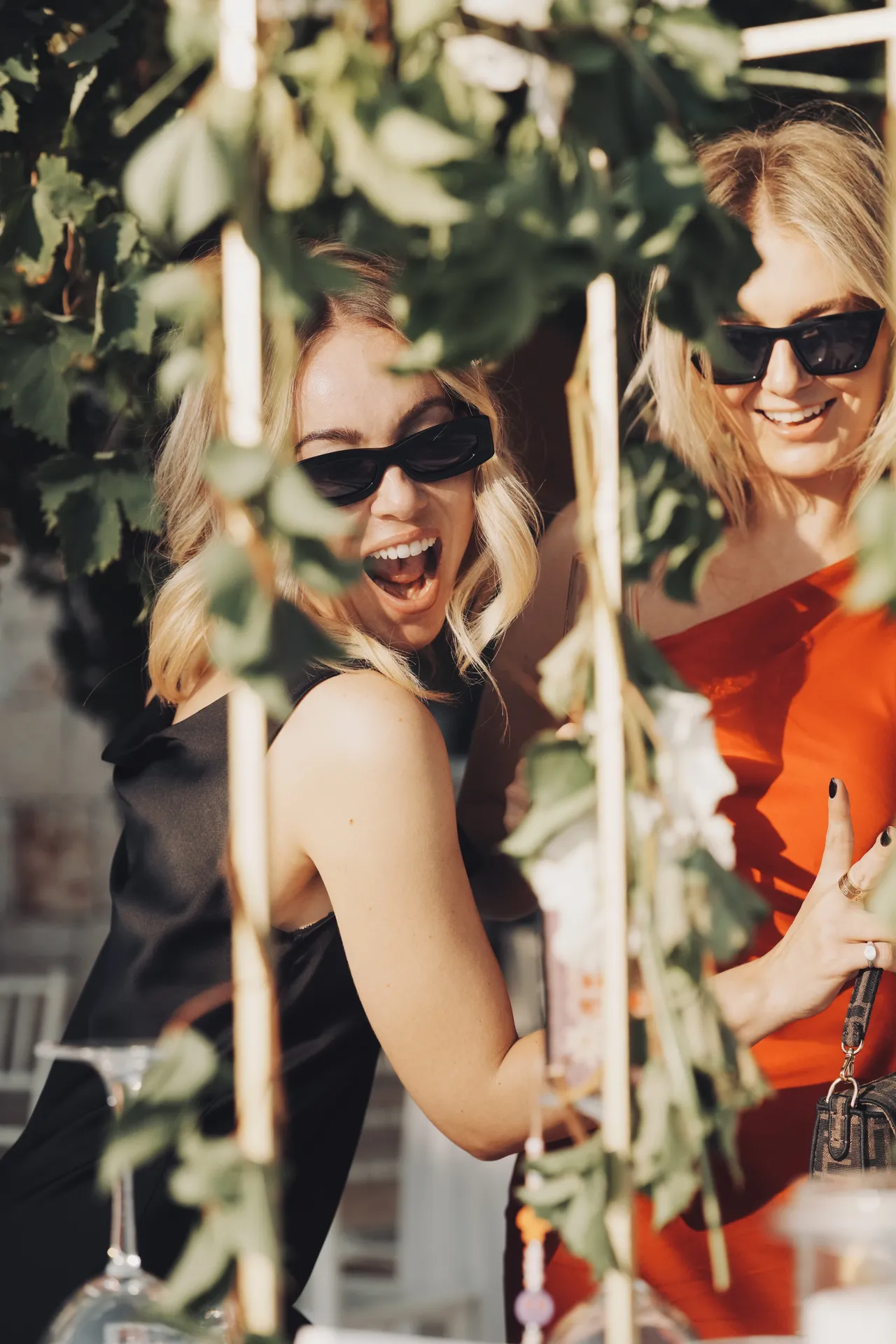 Two stylish female guests laughing in Mediterranean garden