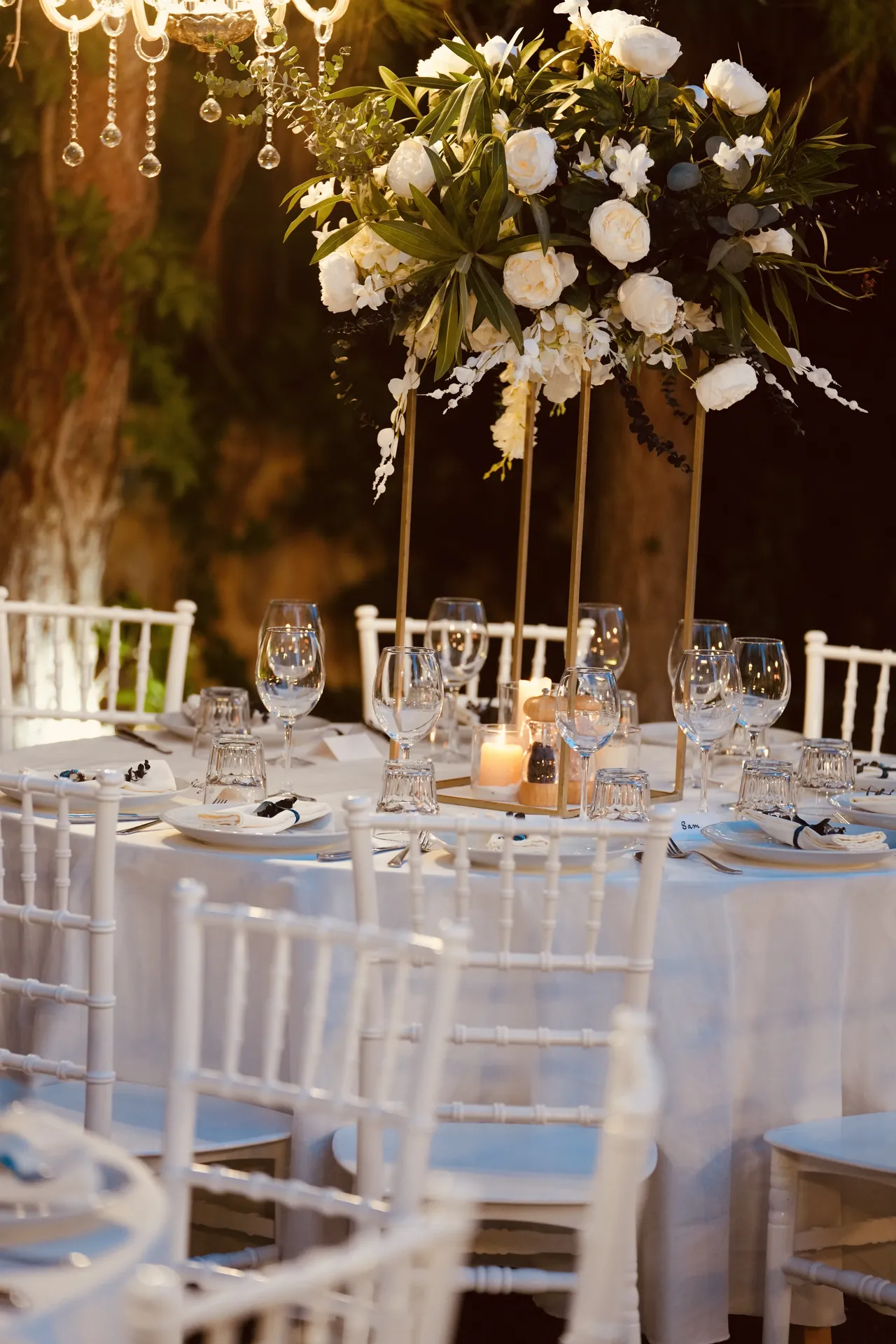 Tall white rose centerpiece beneath crystal chandelier