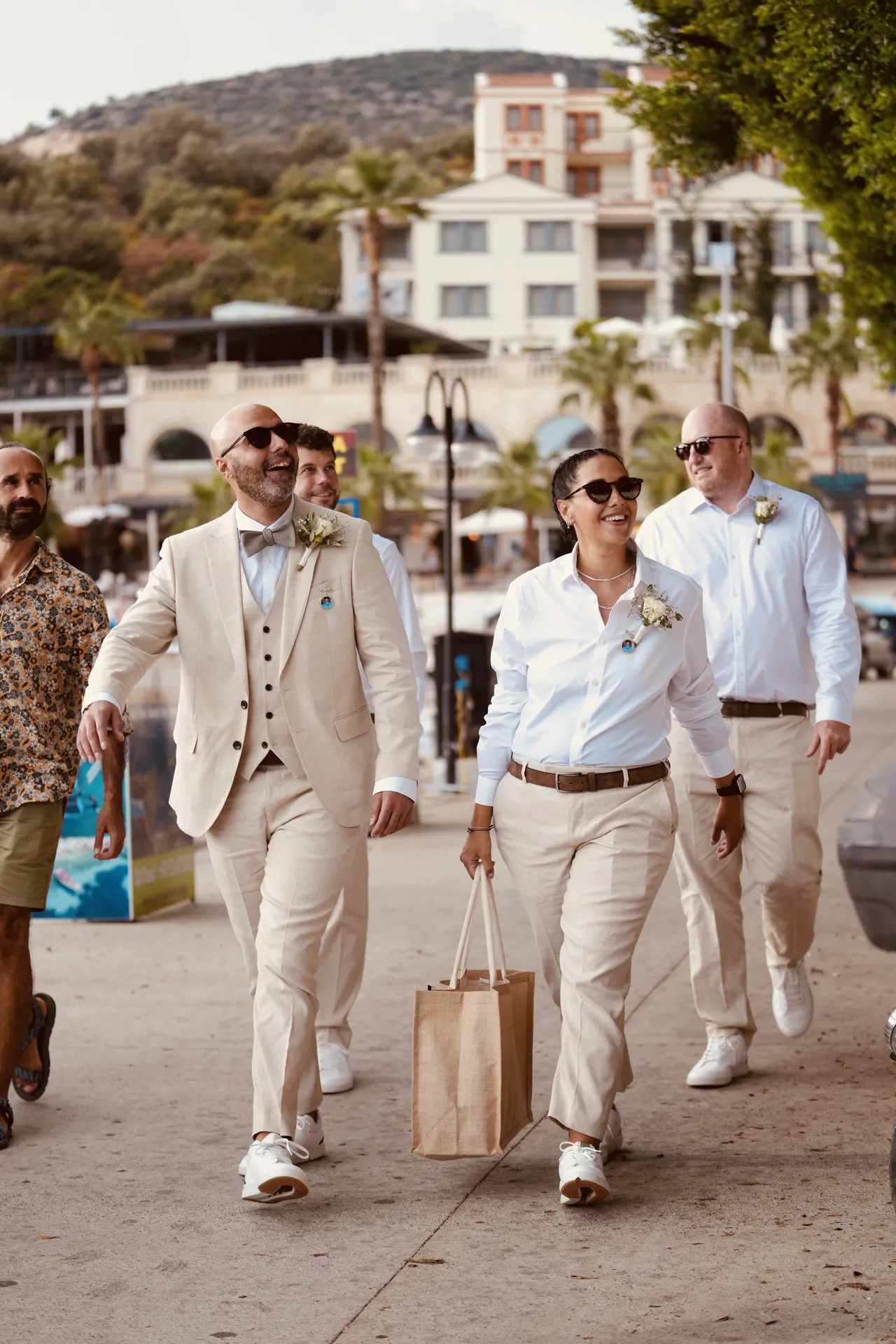 Two grooms in matching beige suits at Mediterranean wedding ceremony