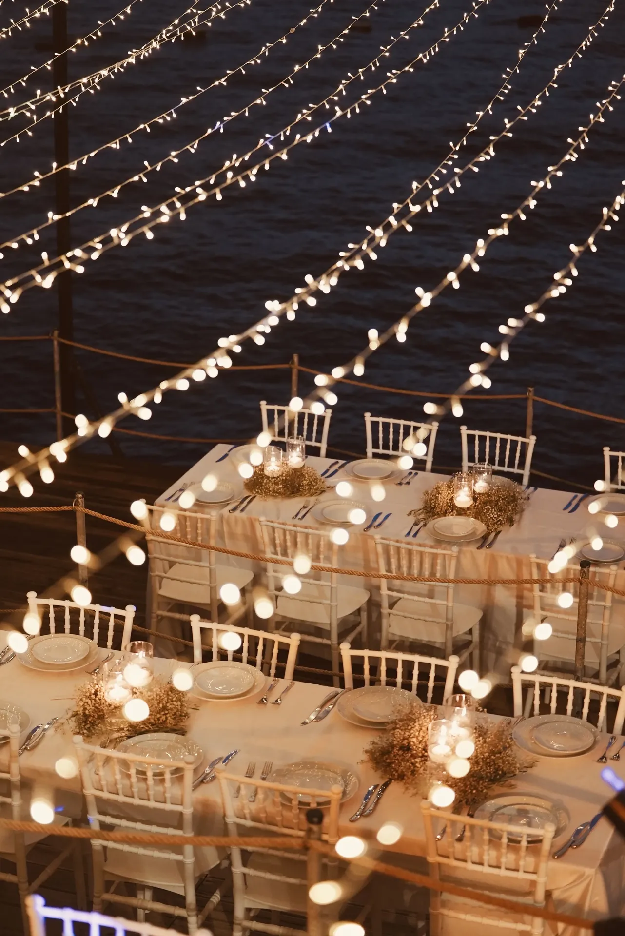 Waterfront reception with baby's breath garlands and string lights